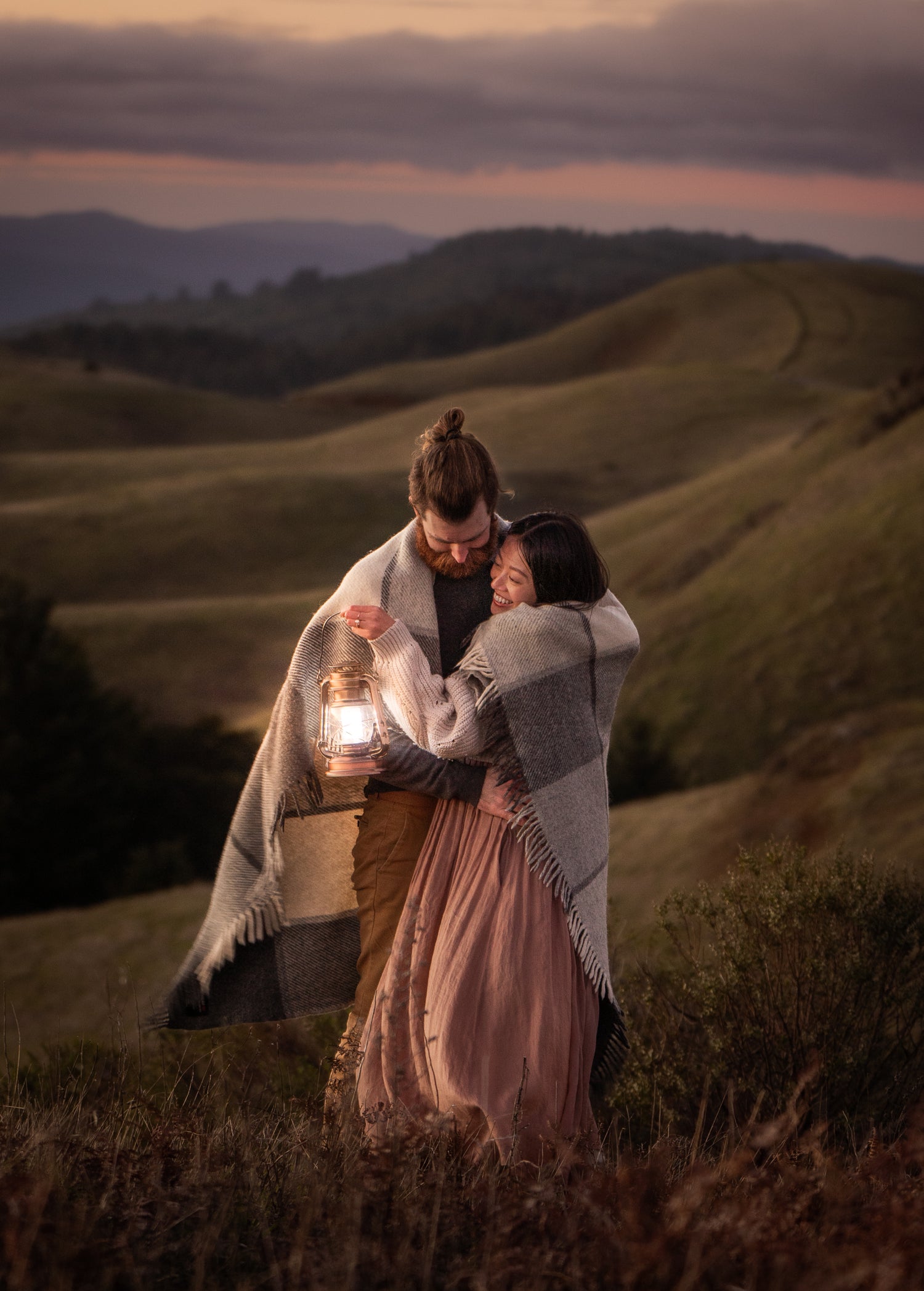 a man and woman holding a lantern, hugging and smiling