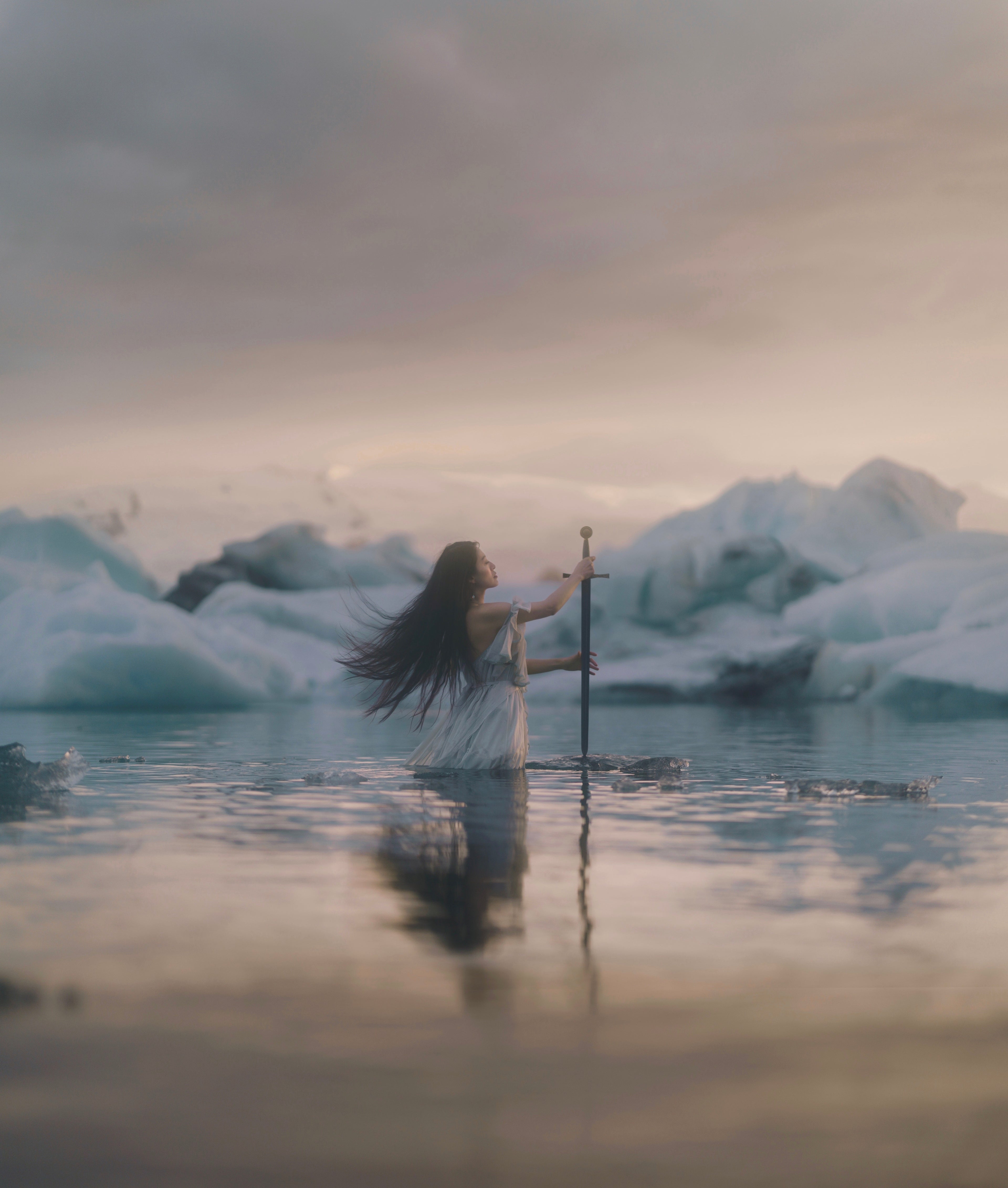 Lady of the Lake - female in a dress pulls Excalibur from an ice flow in a glacier lagoon called Jokulsarlon